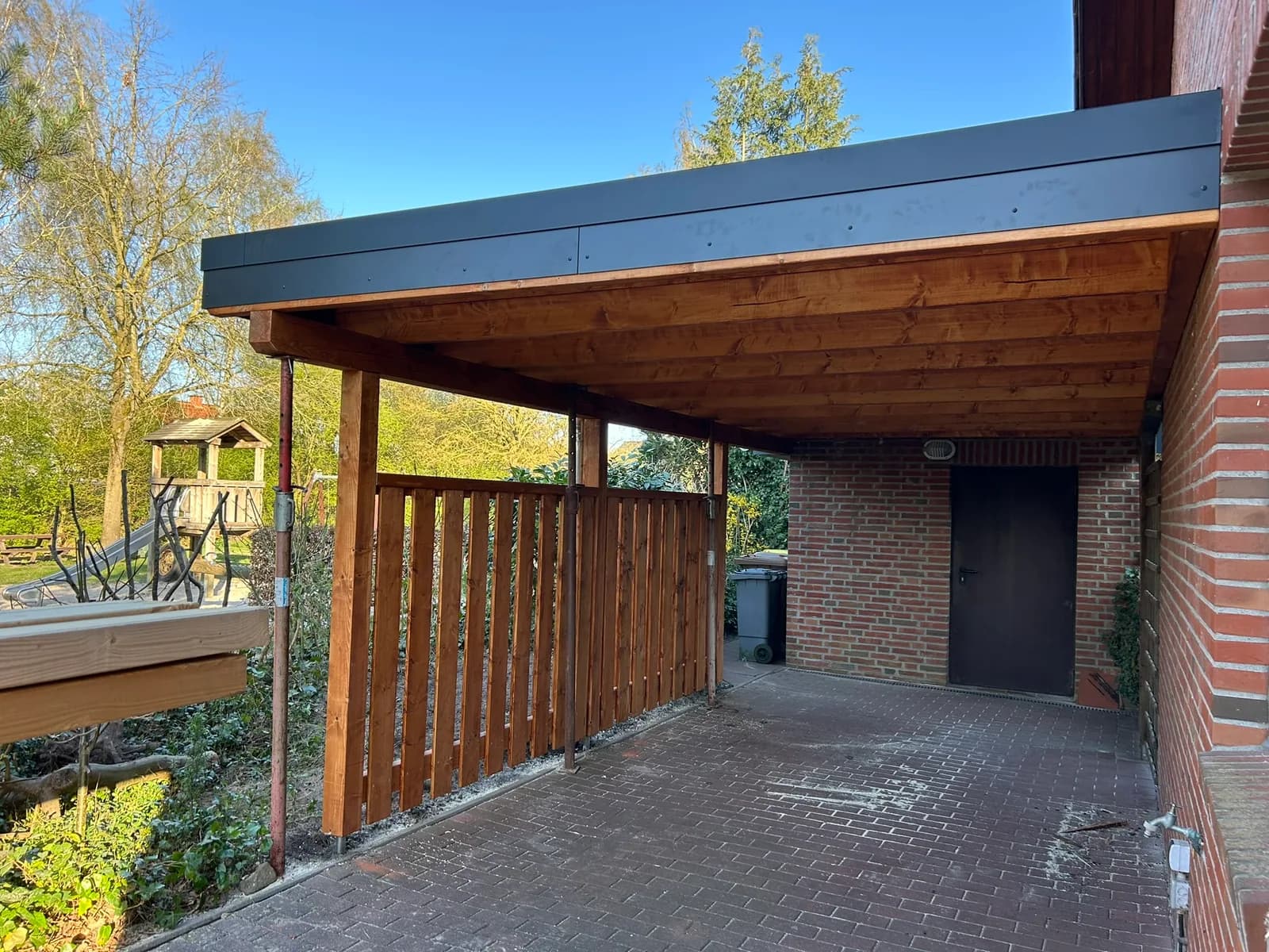 Fertiger Carport an einem Klinkerhaus, sonnige Aufnahme