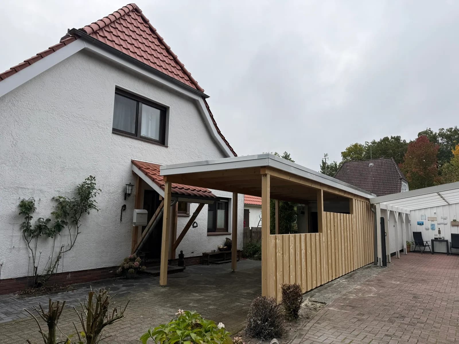 Fertiger heller Carport neben einem weißen Landhaus