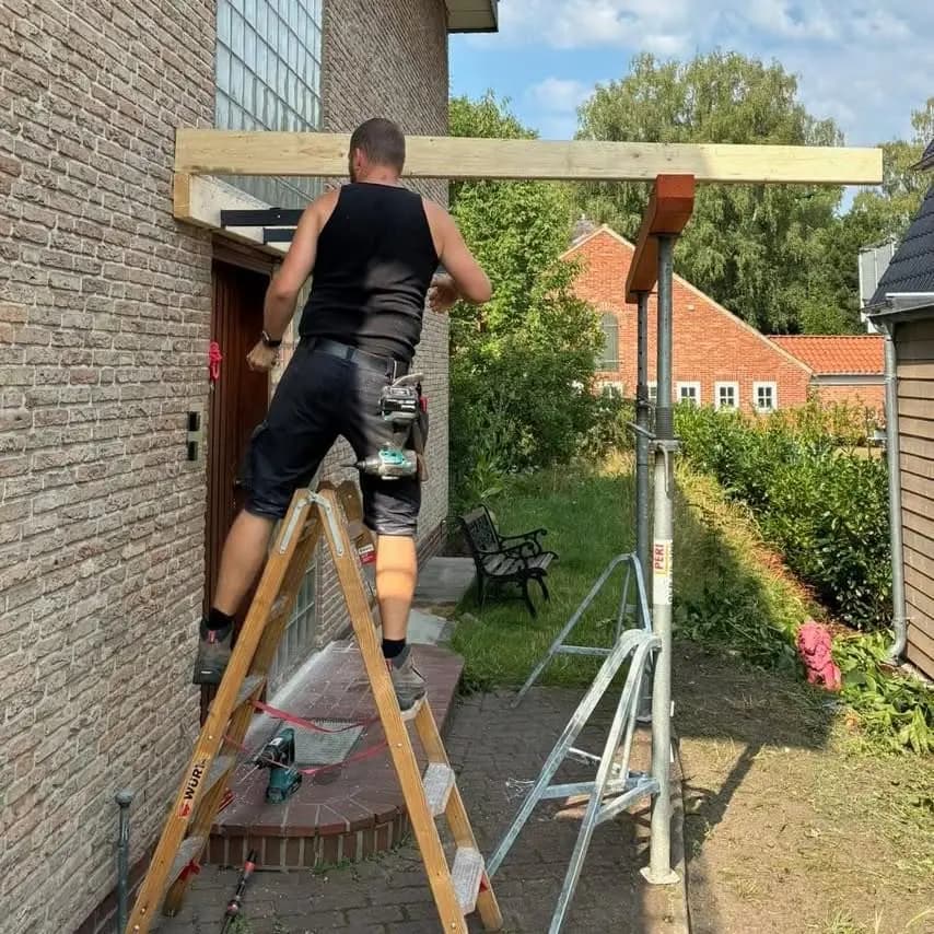 Christoph Stieger montiert auf einer Leiter den neuen Holzbalken der Überdachung