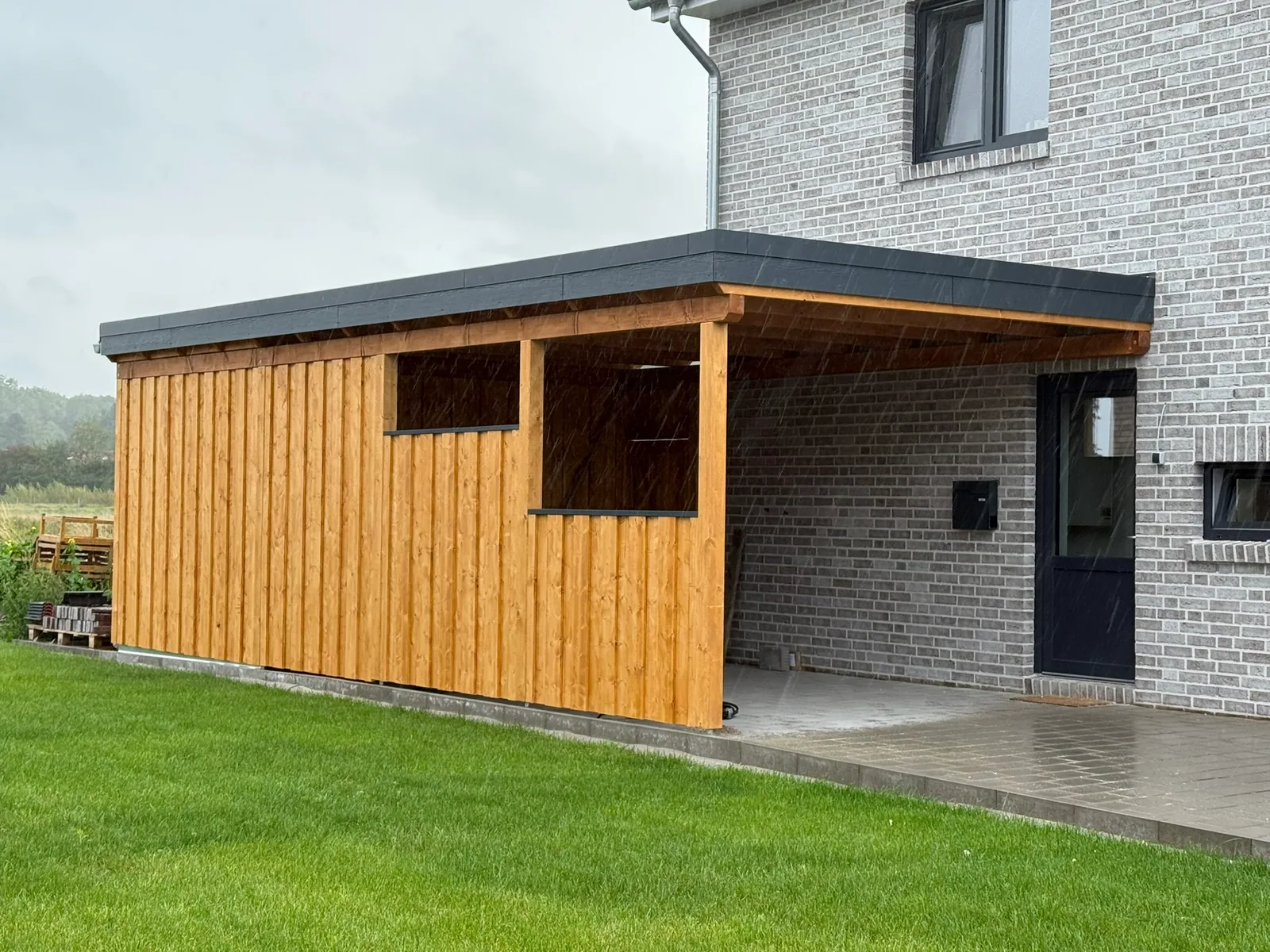 Seitenansicht des Carports mit geschlossener Holzverkleidung und Toren